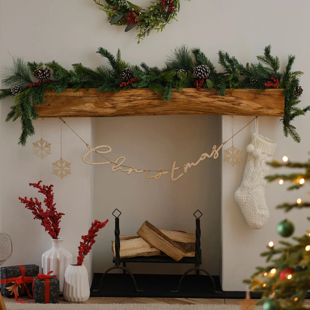 A fireplace decorated ready for christmas with garlands, stocking and pinecones